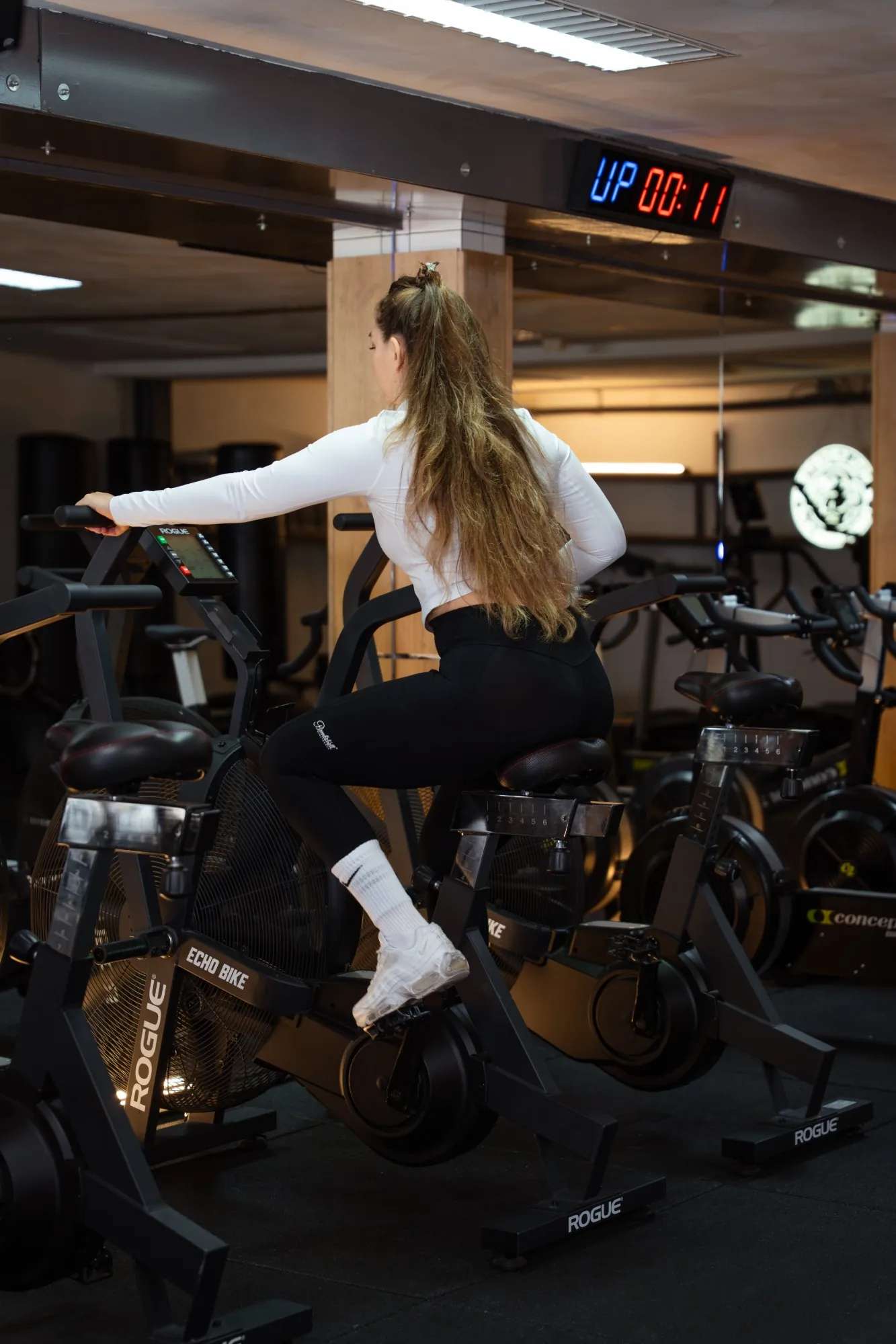Een sporter op de Echo Bike tijdens een groepsles, met de klok boven de spiegel