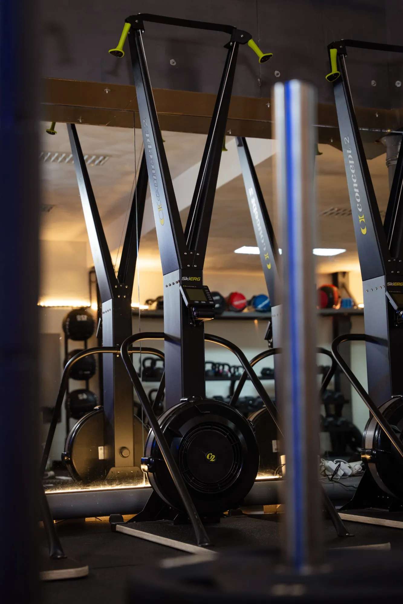 Een SkiErg in warm licht, met kettlebells en wall balls op de achtergrond